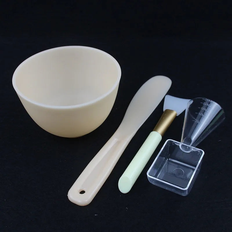 Set of skincare tools including a bowl, spatula, and small container on a black background