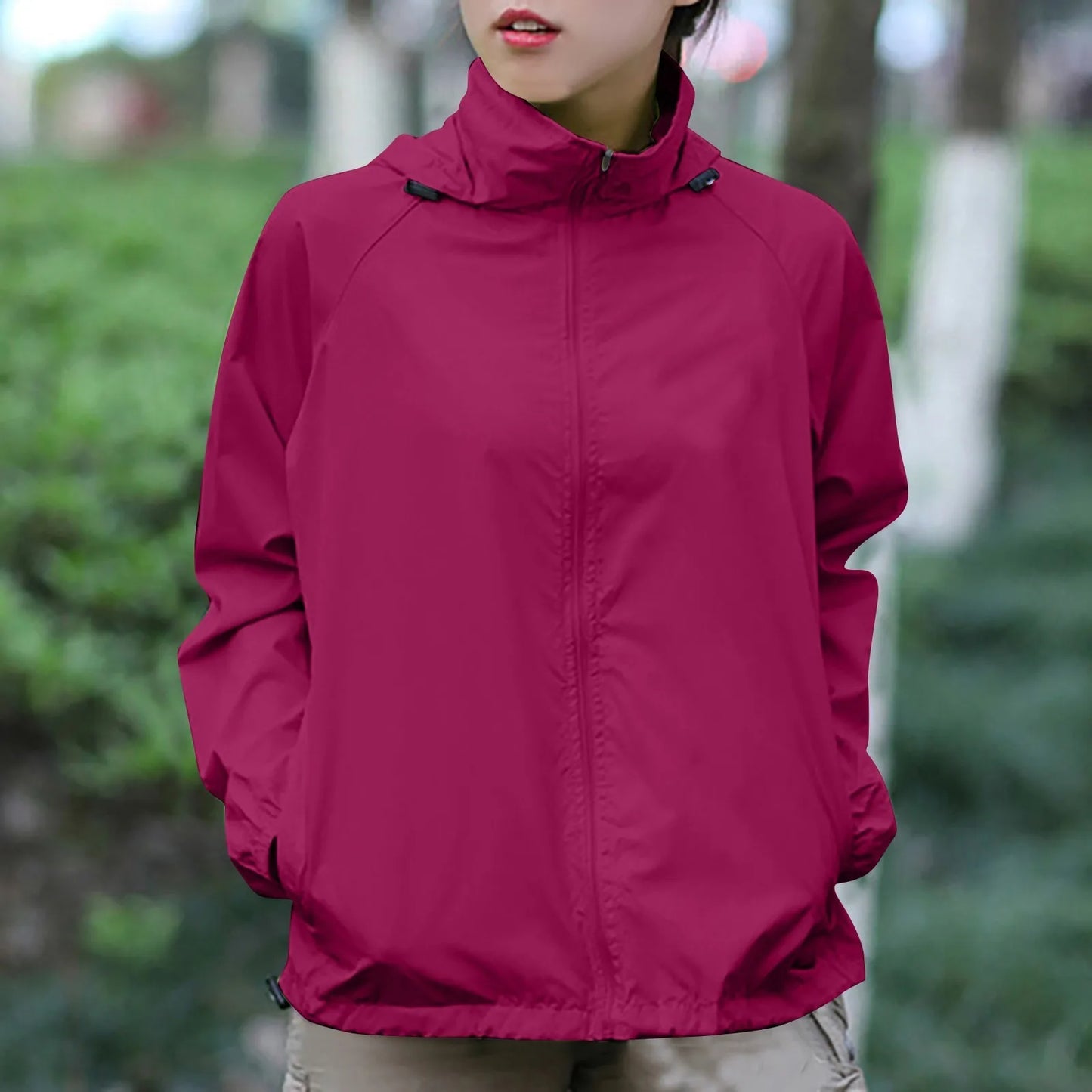 Person wearing a magenta jacket outdoors with greenery in the background