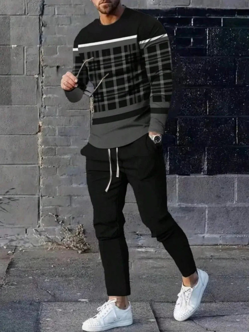 Person wearing a black and gray plaid sweater with black pants and white sneakers against a brick wall.