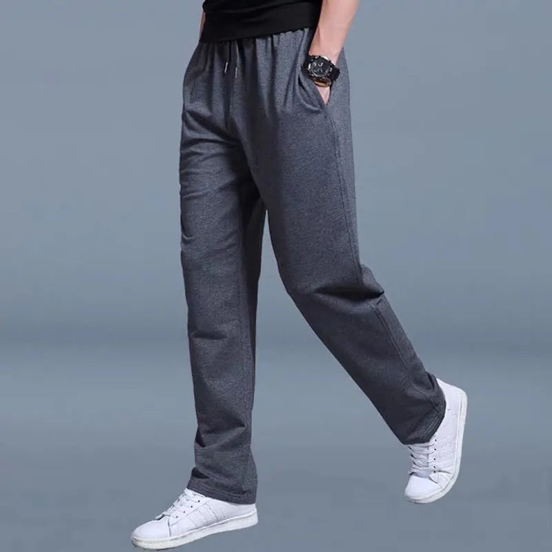Person wearing gray pants and white sneakers on a gray background