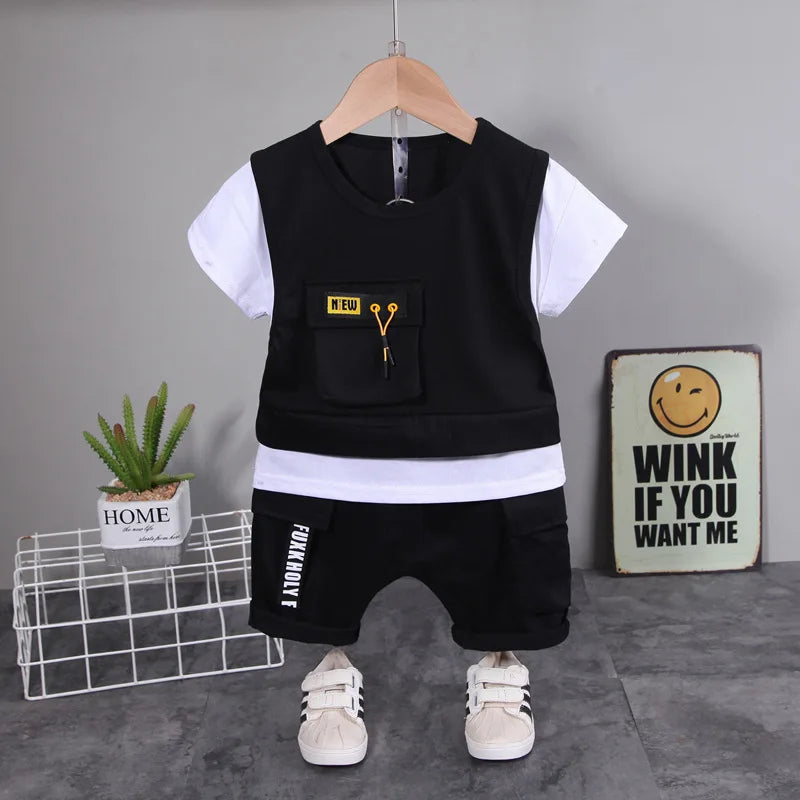 Children's black and white outfit with a vest and shorts on a hanger against a gray background.