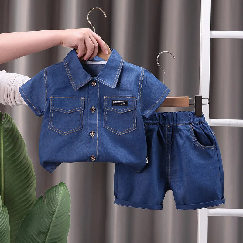Children's blue denim shirt and shorts set on a hanger against a neutral background.