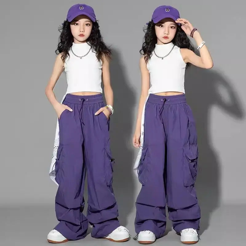 Two poses of a person wearing a white sleeveless top, purple cargo pants, and a purple cap on a gray background.