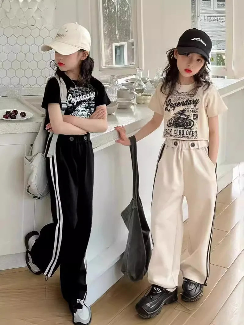 Two children in stylish outfits standing in a kitchen.