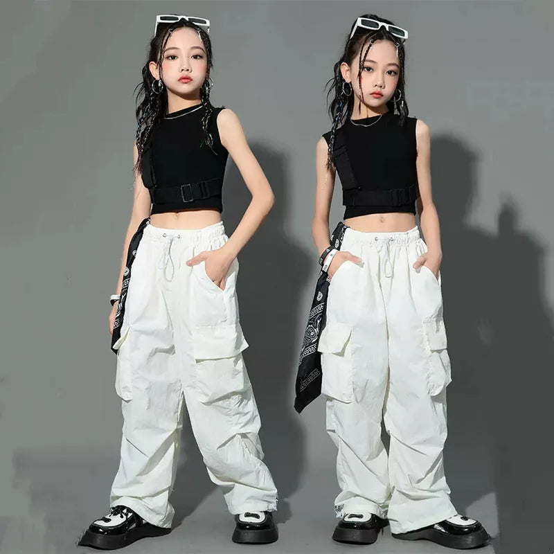 Two identical images of a person wearing a black sleeveless top and white cargo pants on a gray background.