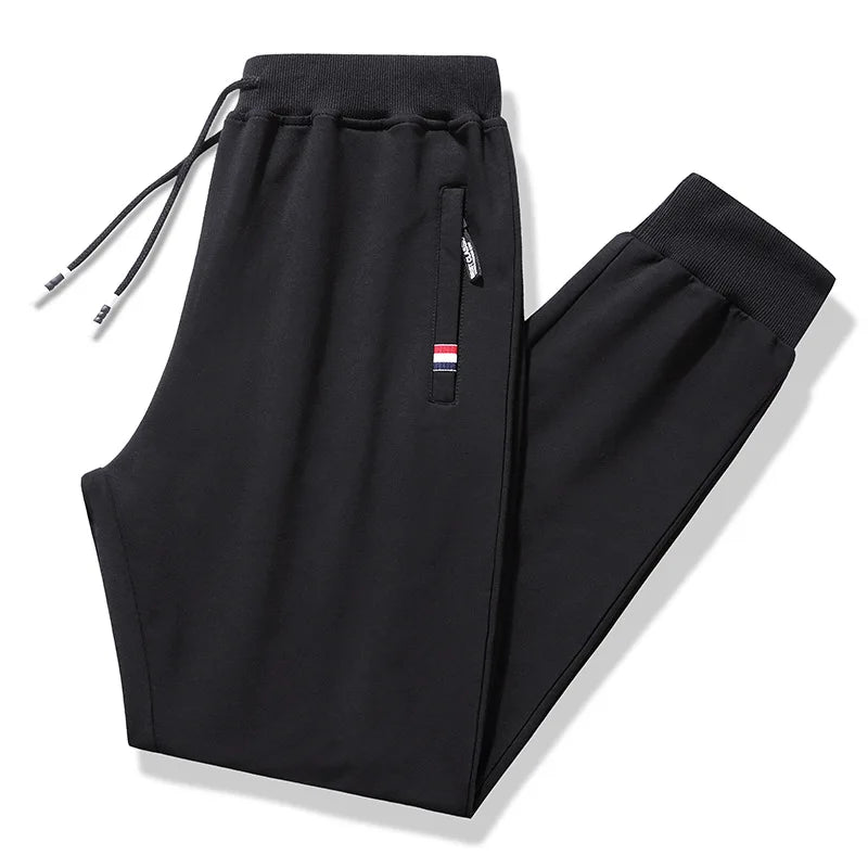Black drawstring pants with a small flag patch on a white background