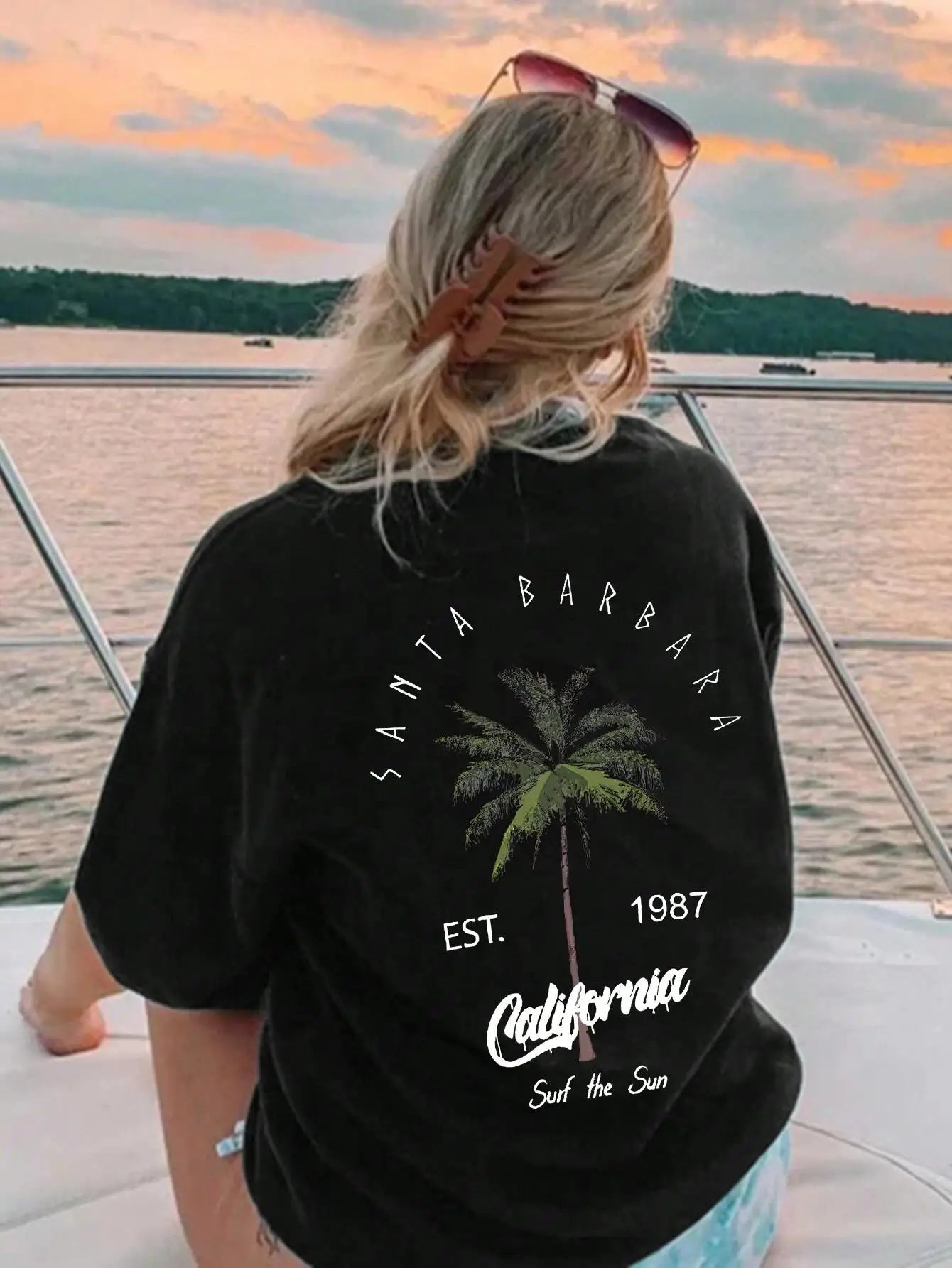 Person wearing a black t-shirt with 'Santa Barbara, California' text and palm tree graphic, standing on a boat.