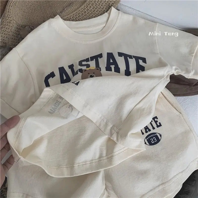 Beige t-shirt with 'CALSTATE' text and bear graphic, held by a hand.