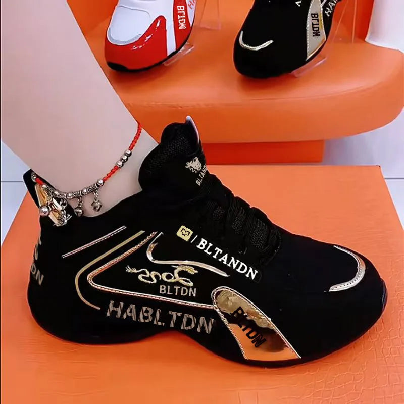 Black sneaker with gold accents and branding on an orange surface