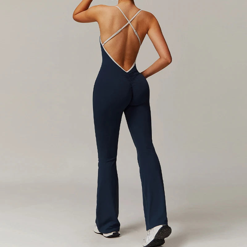 Person wearing a navy blue jumpsuit with a backless design on a plain background