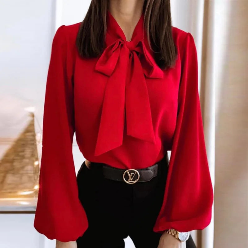 Red blouse with a large bow and black pants worn by a person.