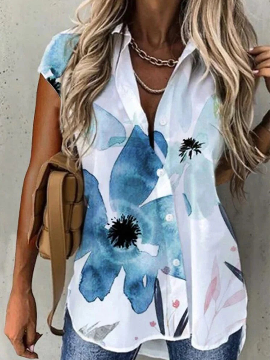 Woman wearing a white shirt with blue floral patterns, holding a beige bag.