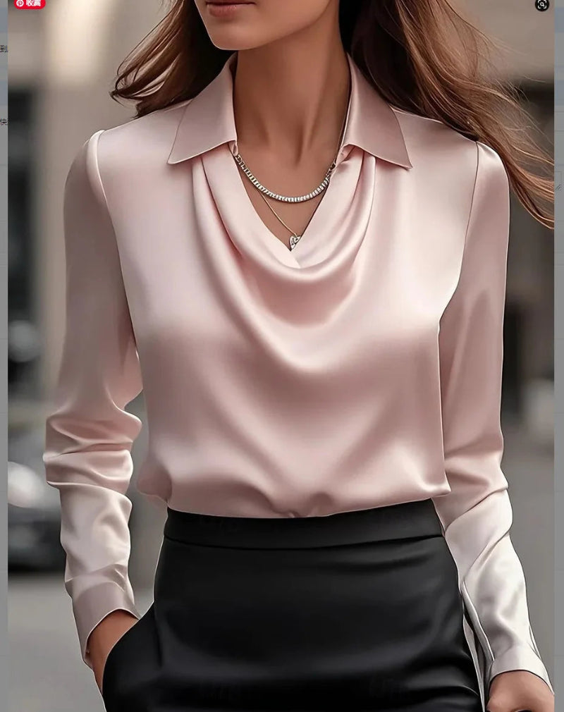 Person wearing a light pink blouse with long sleeves and a black skirt, standing outdoors.