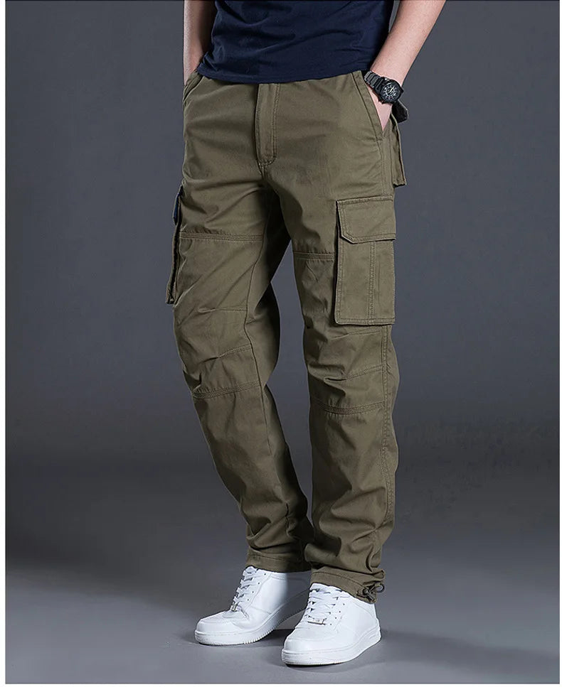 Person wearing olive green cargo pants on a gray background