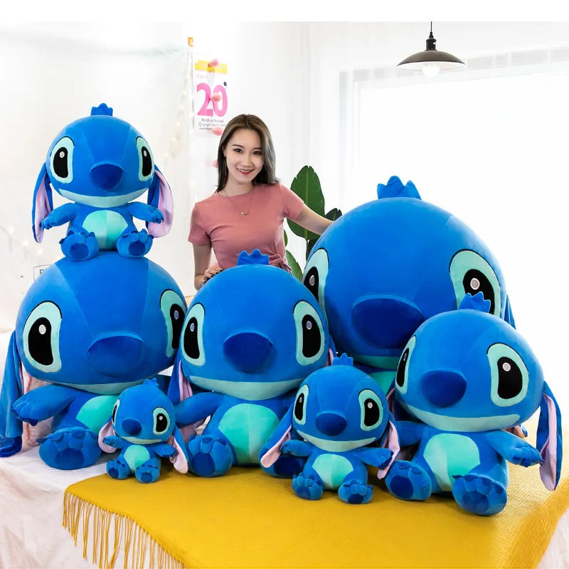 Woman with a collection of blue plush toys resembling a character on a yellow surface.