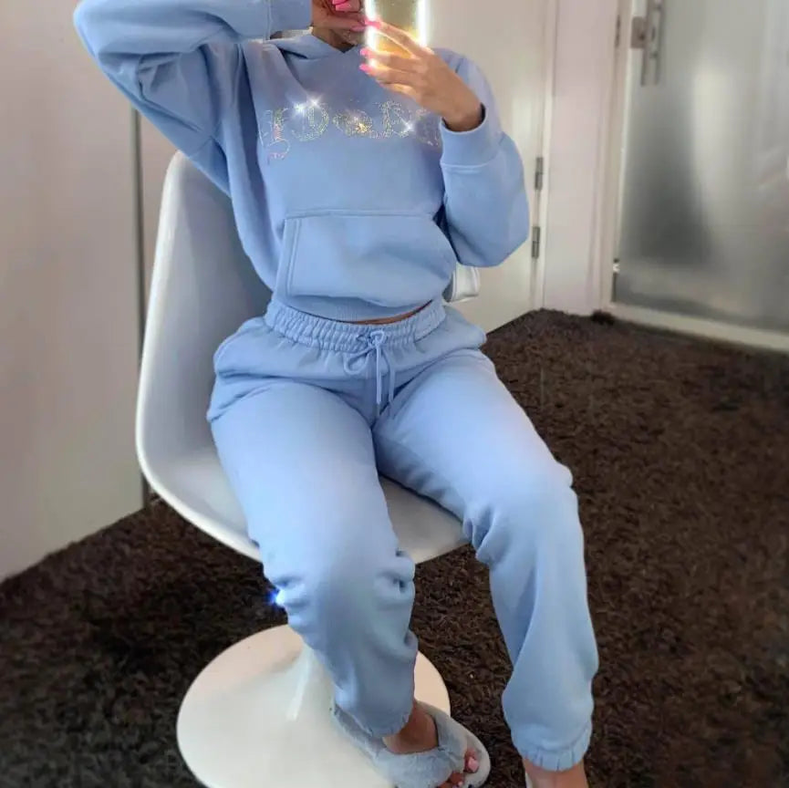 Person wearing a light blue tracksuit sitting on a white chair.