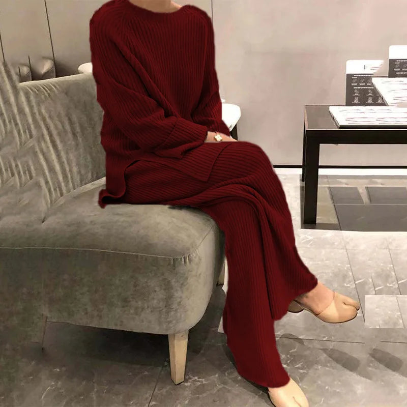 Person wearing a red knit outfit sitting on a gray sofa in an indoor setting.