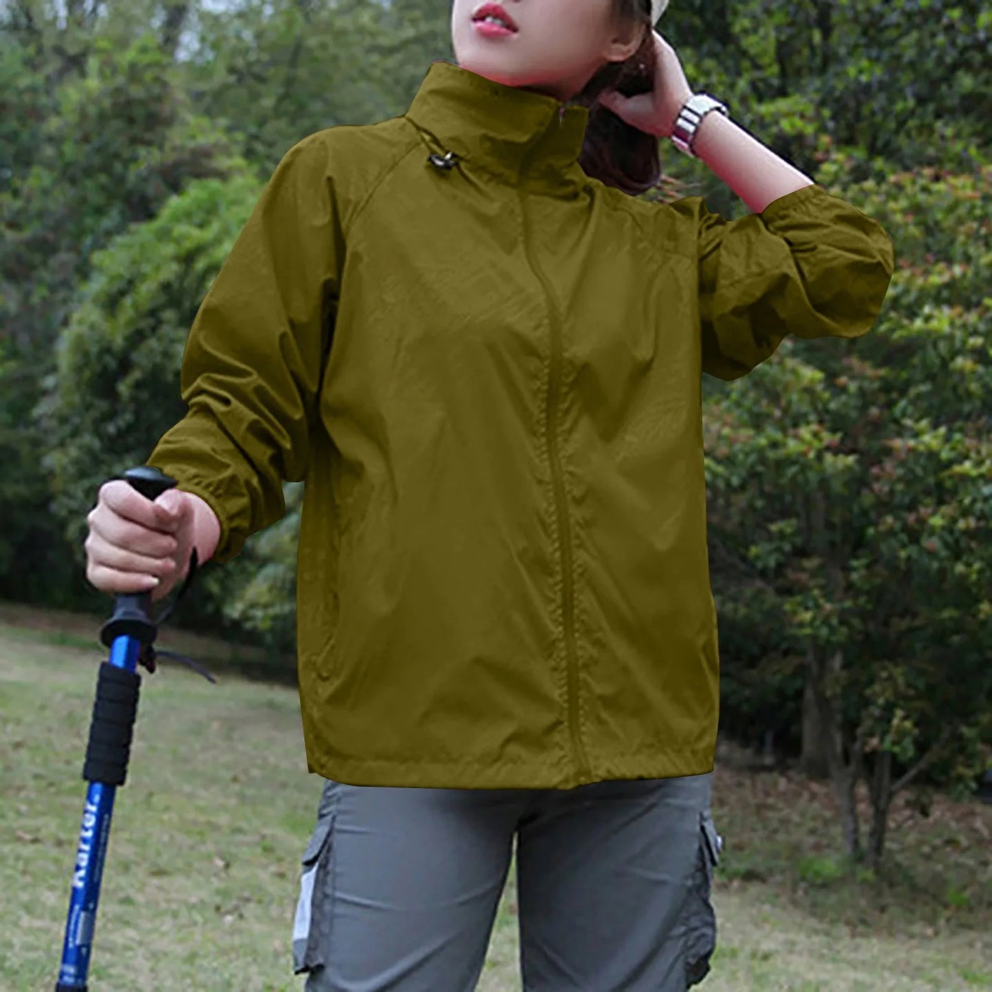 Person wearing a green jacket holding a walking stick outdoors