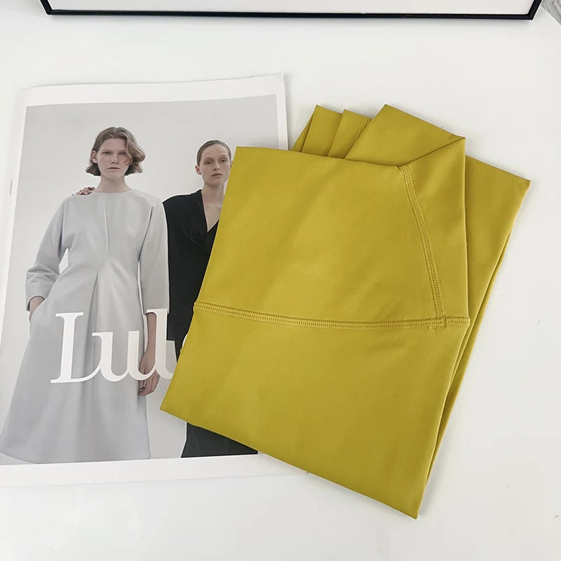 Mustard yellow fabric on a white surface with a magazine featuring two women in dresses.