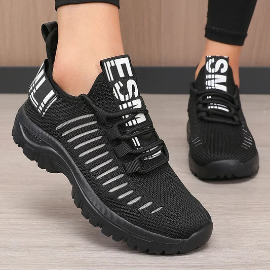 Black athletic shoes with white text on a wooden floor