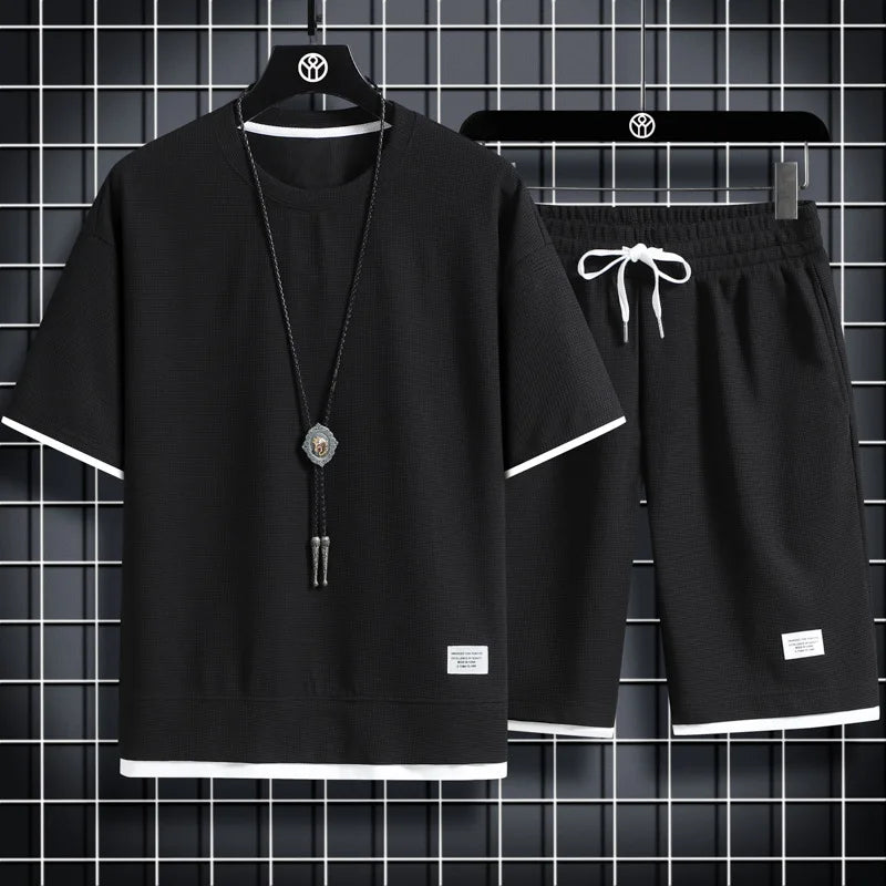 Black t-shirt and shorts set with a necklace on a hanger against a grid background