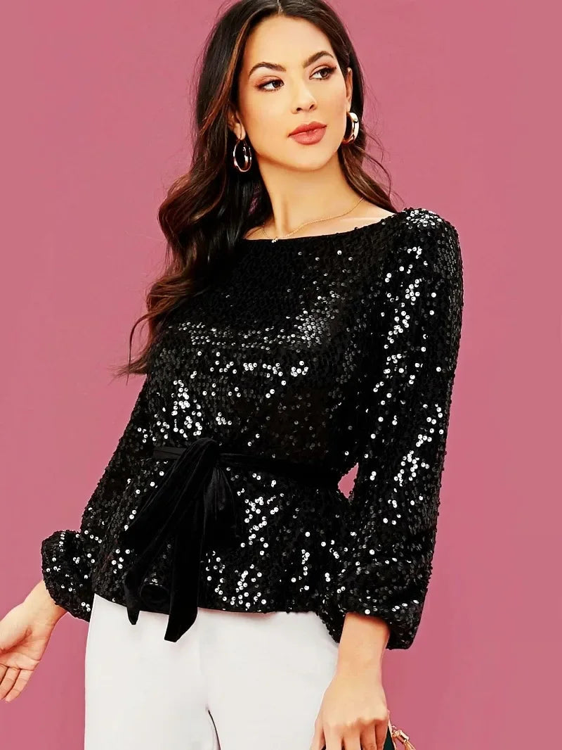 Woman wearing a black sequin top against a pink background