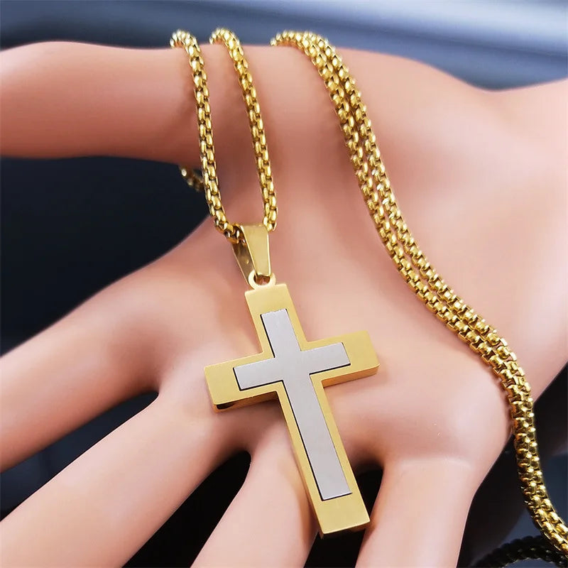 Gold and silver cross pendant on a gold chain held in a hand against a dark background