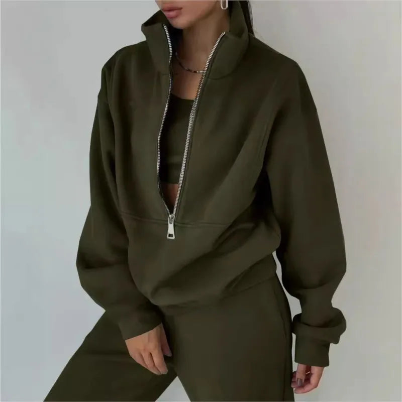 Person wearing a green tracksuit with a zipper on a plain background