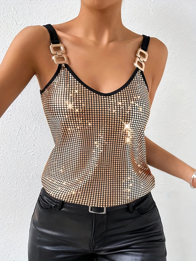 Woman wearing a sparkly top with gold and black straps against a white background