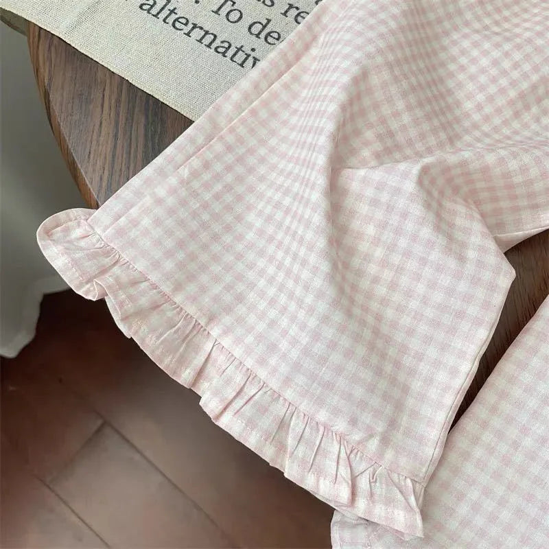 Pink checkered fabric with ruffled edge on a wooden surface