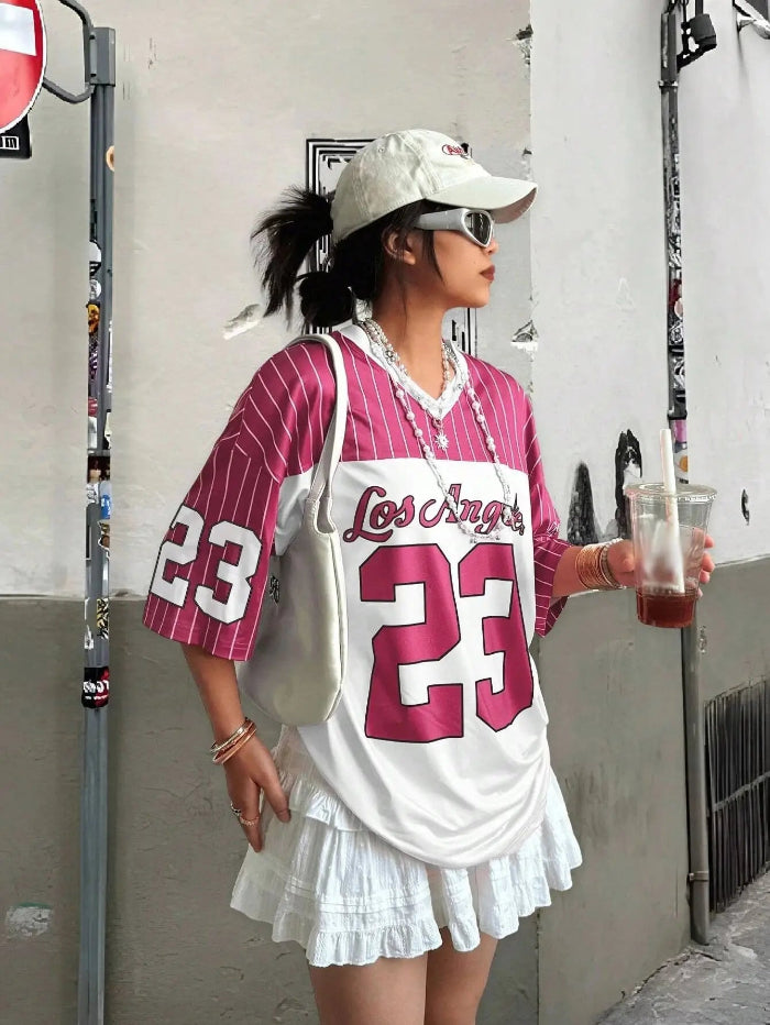 A person wearing a white V-neck T-shirt with the number 23 printed in black, paired with a white skirt, white hat, and holding a drink.