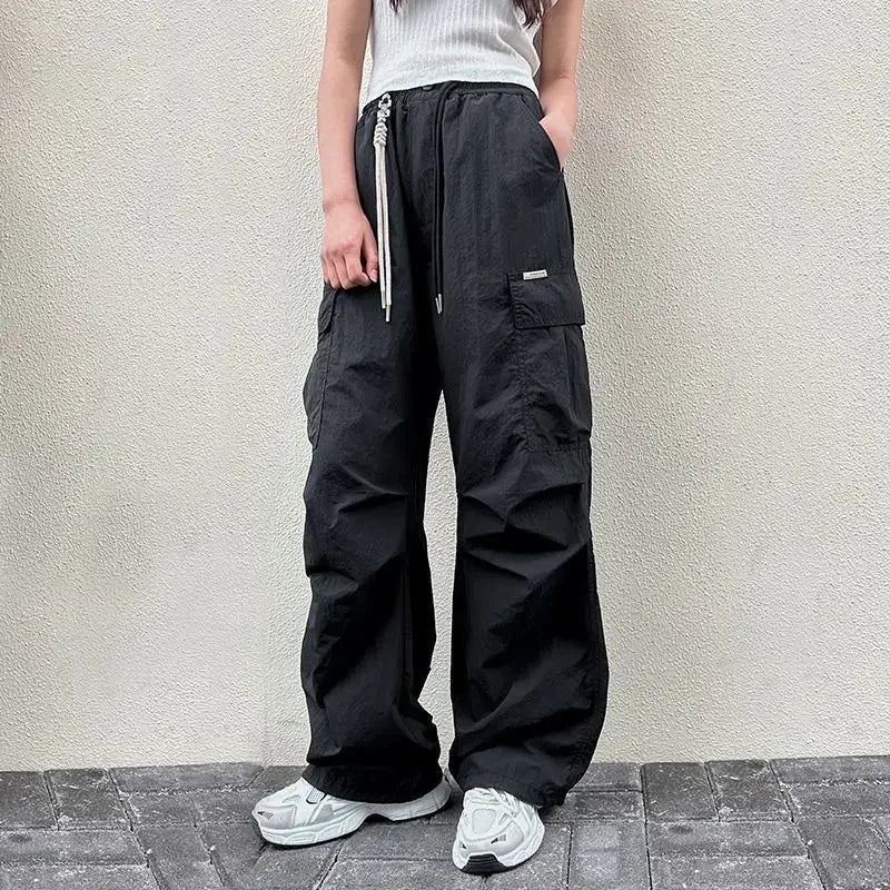 Person wearing black cargo pants standing against a light-colored wall.