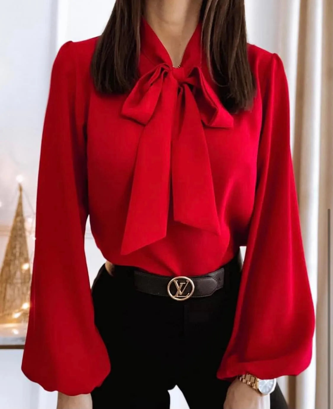 Red blouse with a large bow tie worn by a person, with a blurred background.