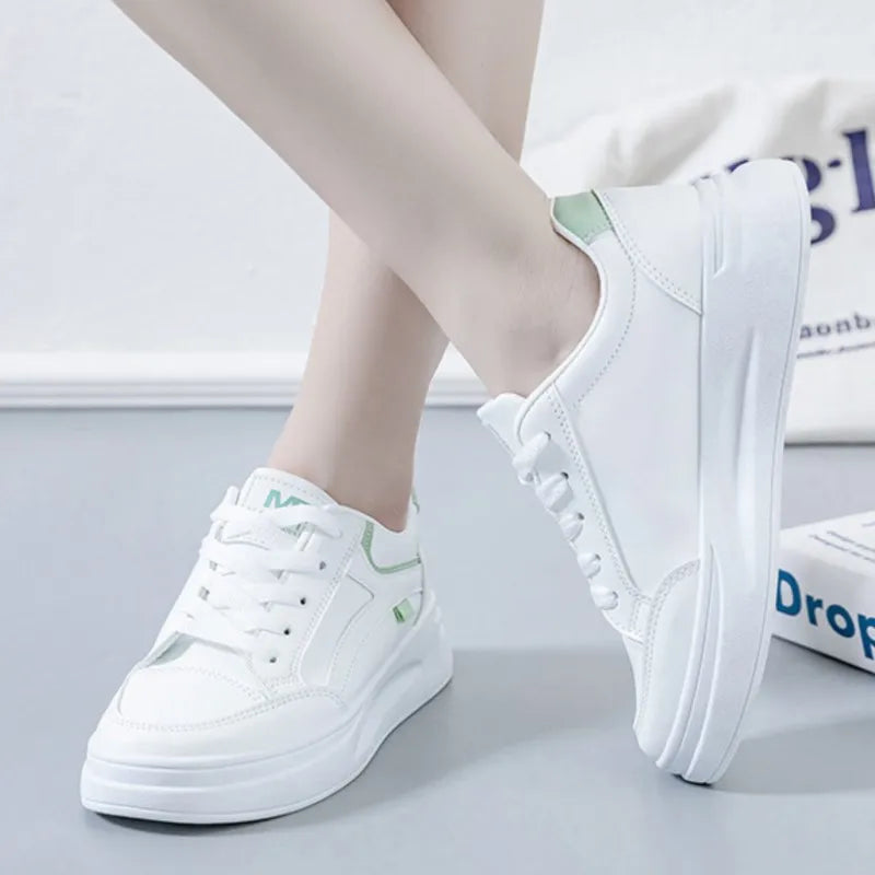 White sneakers with green accents worn by a person on a light gray background