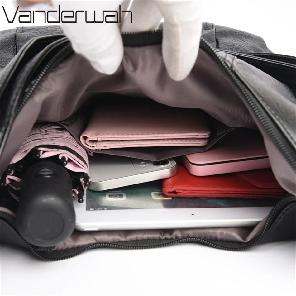 Open bag with electronic devices and a pink umbrella, featuring the brand 'Vanderwah'.