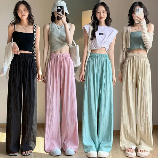 Four women wearing different colored wide-leg pants with matching tops.