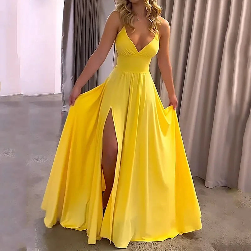 Woman wearing a yellow evening gown with a slit in a room with gray curtains.