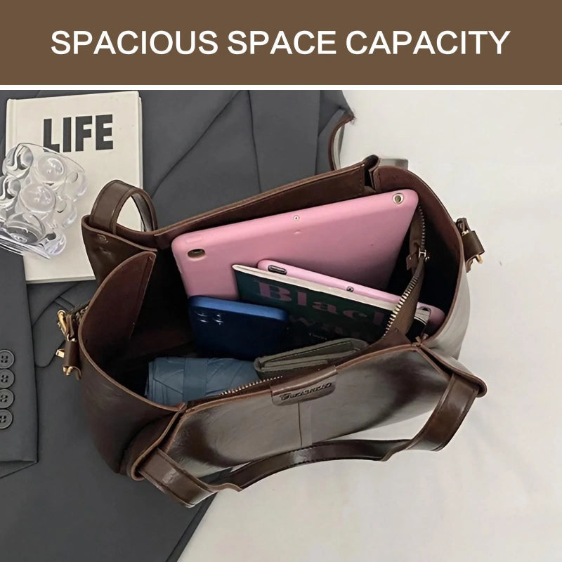Brown leather bag with electronic devices inside, on a neutral background