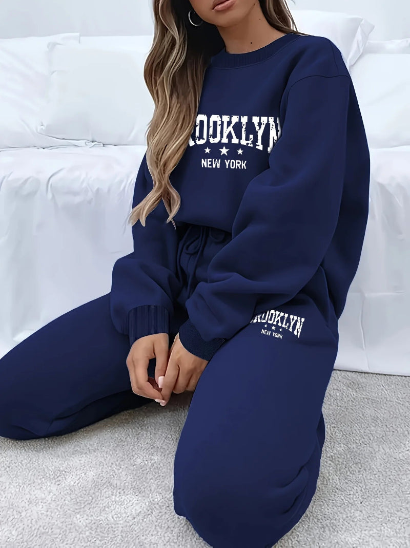 Person wearing a navy blue 'Brooklyn New York' sweatshirt and pants on a white couch.