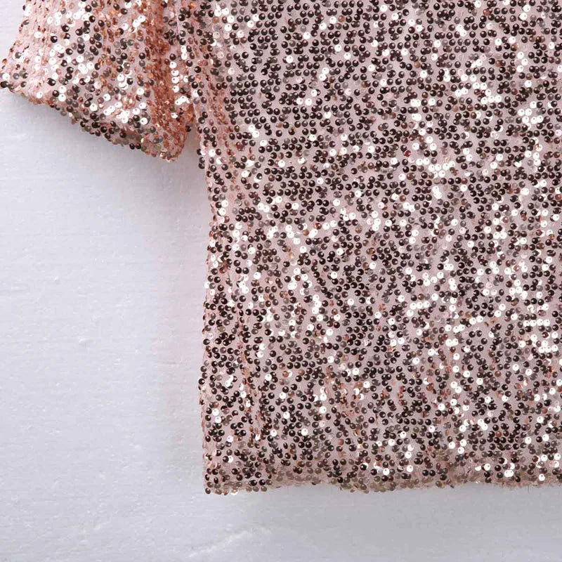 Close-up of a rose gold sequin fabric on a light gray background