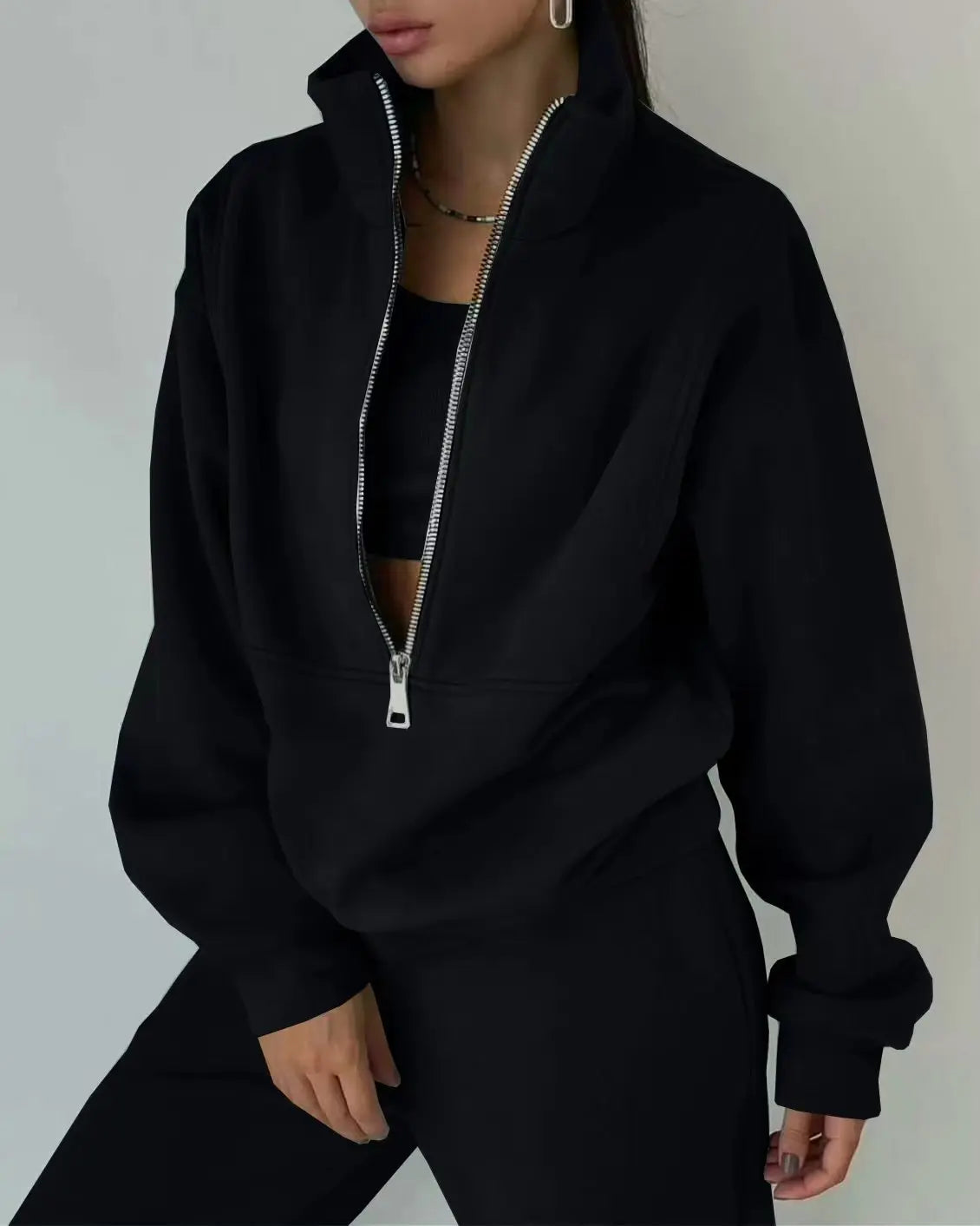 Person wearing a black zip-up hoodie against a neutral background