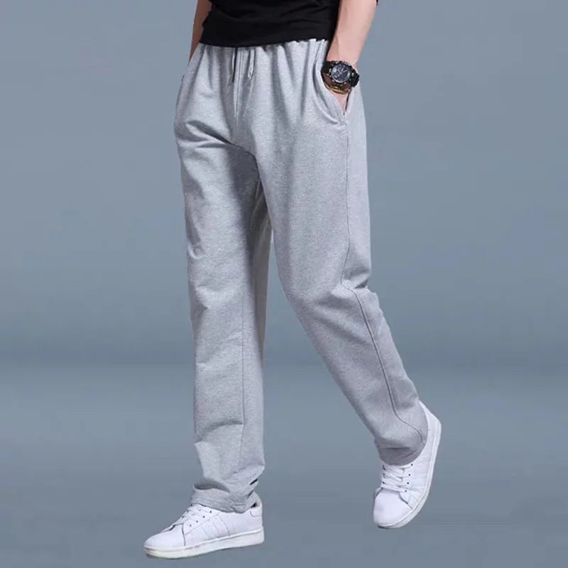 Person wearing gray sweatpants and white sneakers on a gray background
