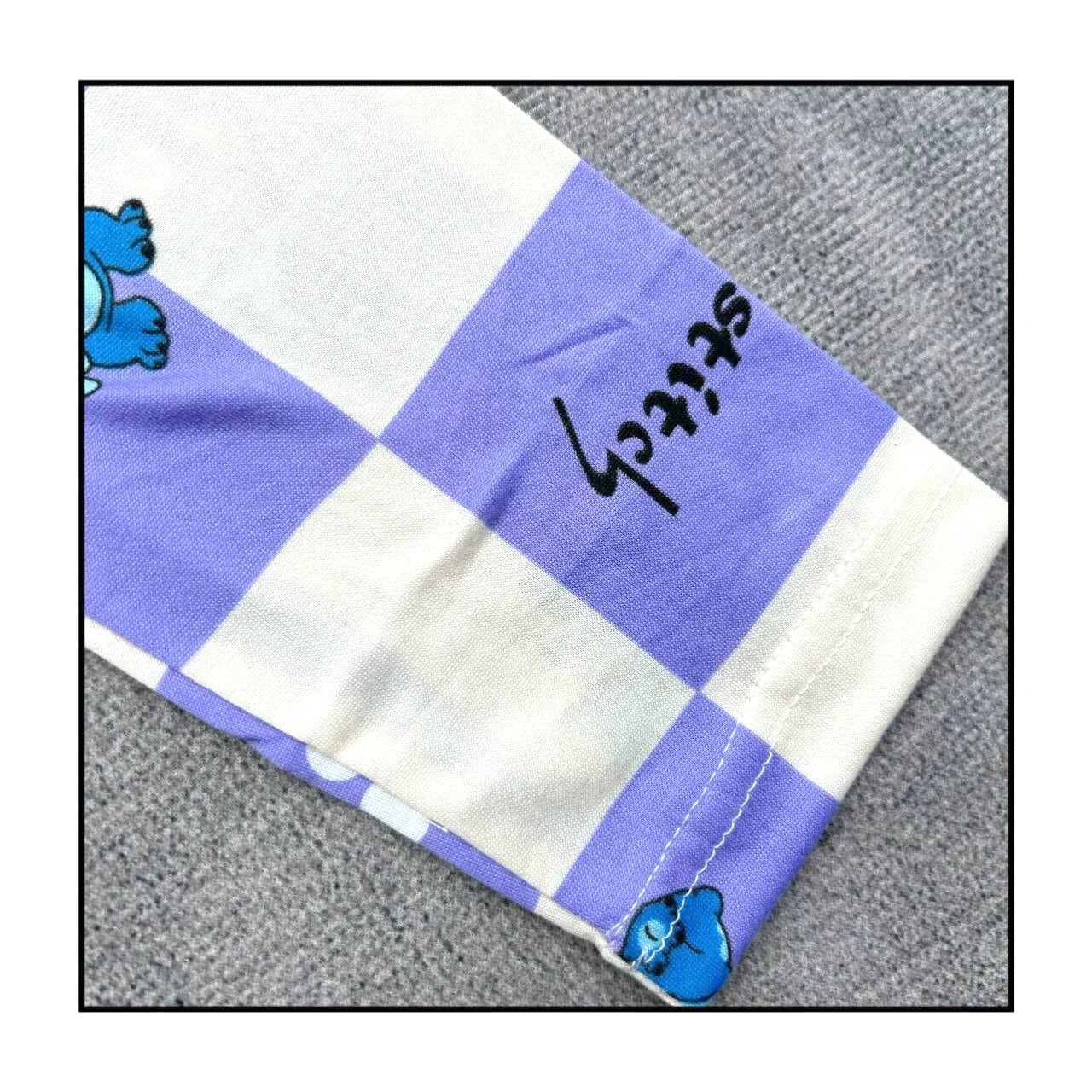 Checkered fabric with blue and white squares, featuring a blue turtle design and black text on a gray background.