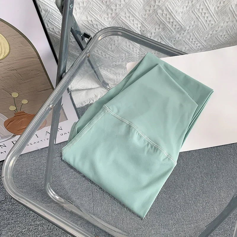 Folded light green fabric on a clear plastic chair with a textured gray surface underneath.