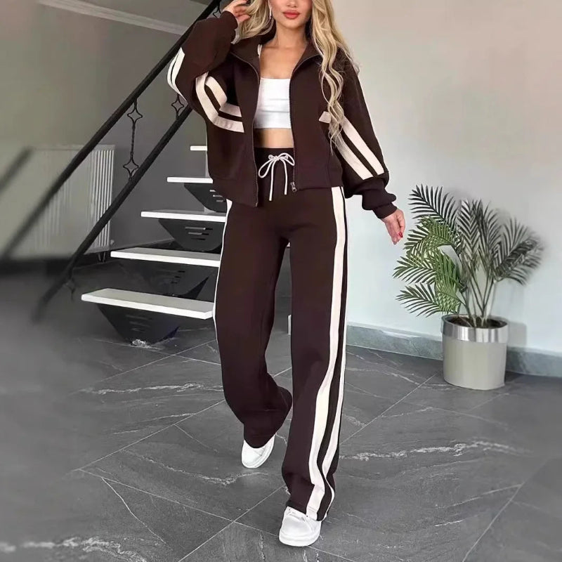Woman in a brown tracksuit with white stripes walking in a modern interior setting.