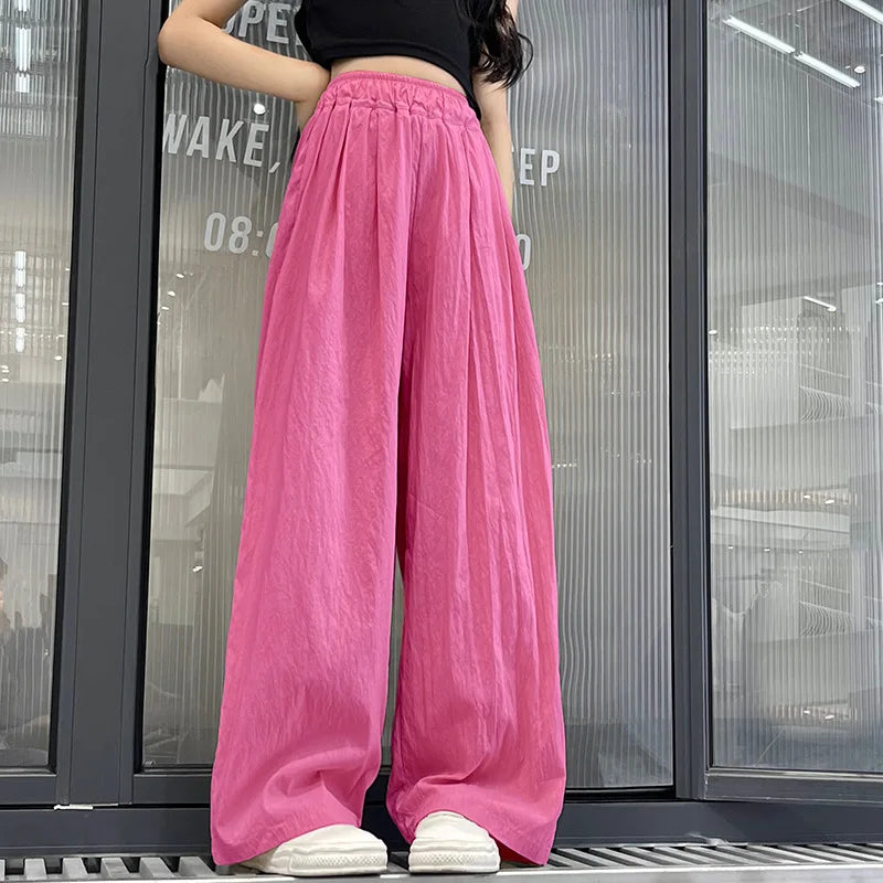 Person wearing bright pink wide-leg pants in front of a glass door.