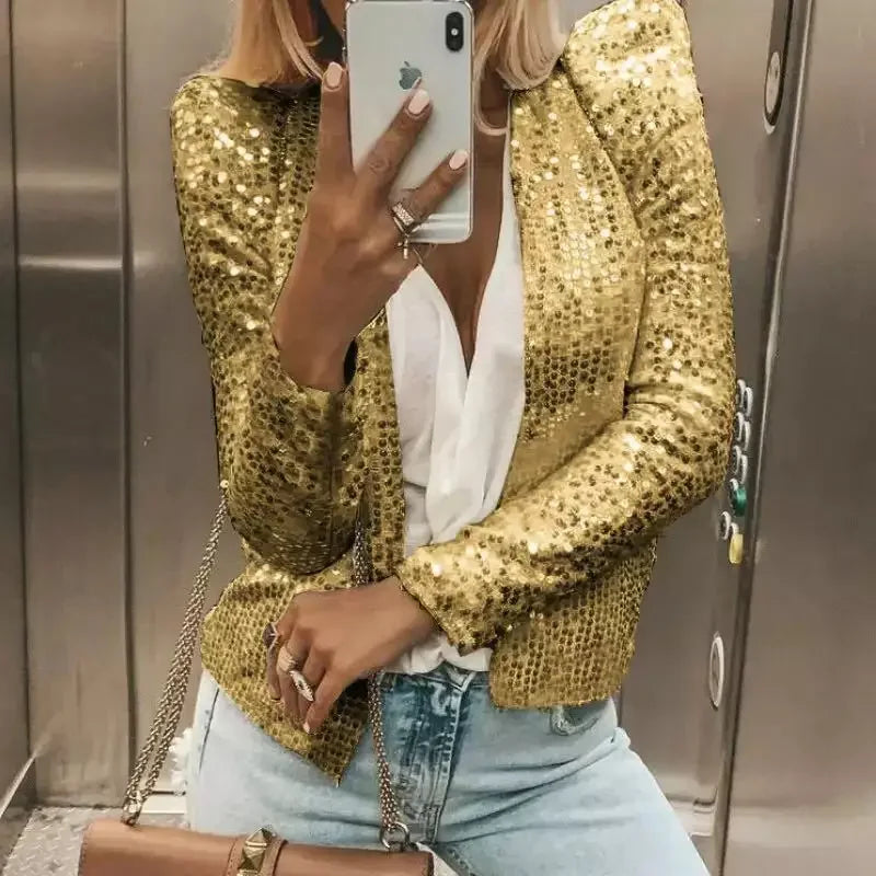Person wearing a gold sequin jacket and light blue jeans, taking a mirror selfie.