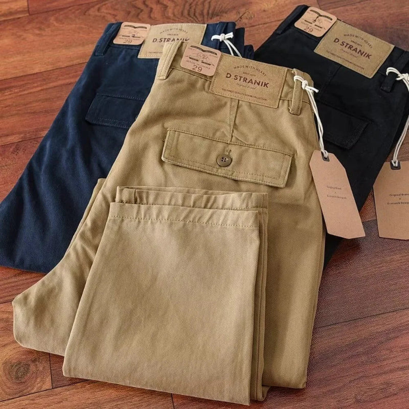 Three pairs of pants in navy, beige, and black on a wooden surface with Stranik brand tags.