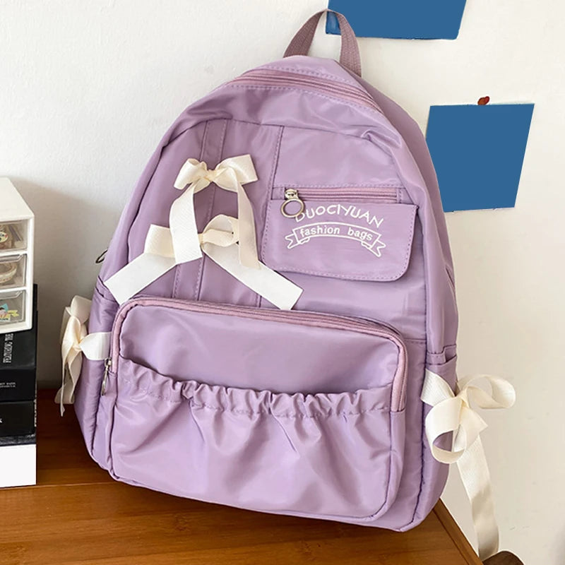 Purple backpack with white ribbons on a wooden surface