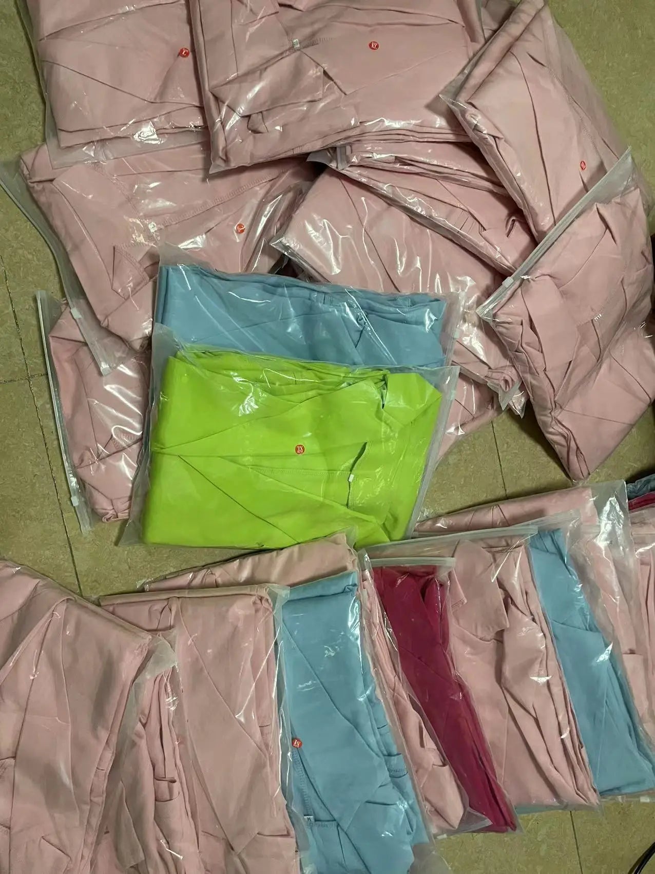Pink and blue fabric samples in clear plastic bags on a green surface